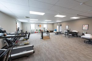 Large open room with exercise equipment and massage beds